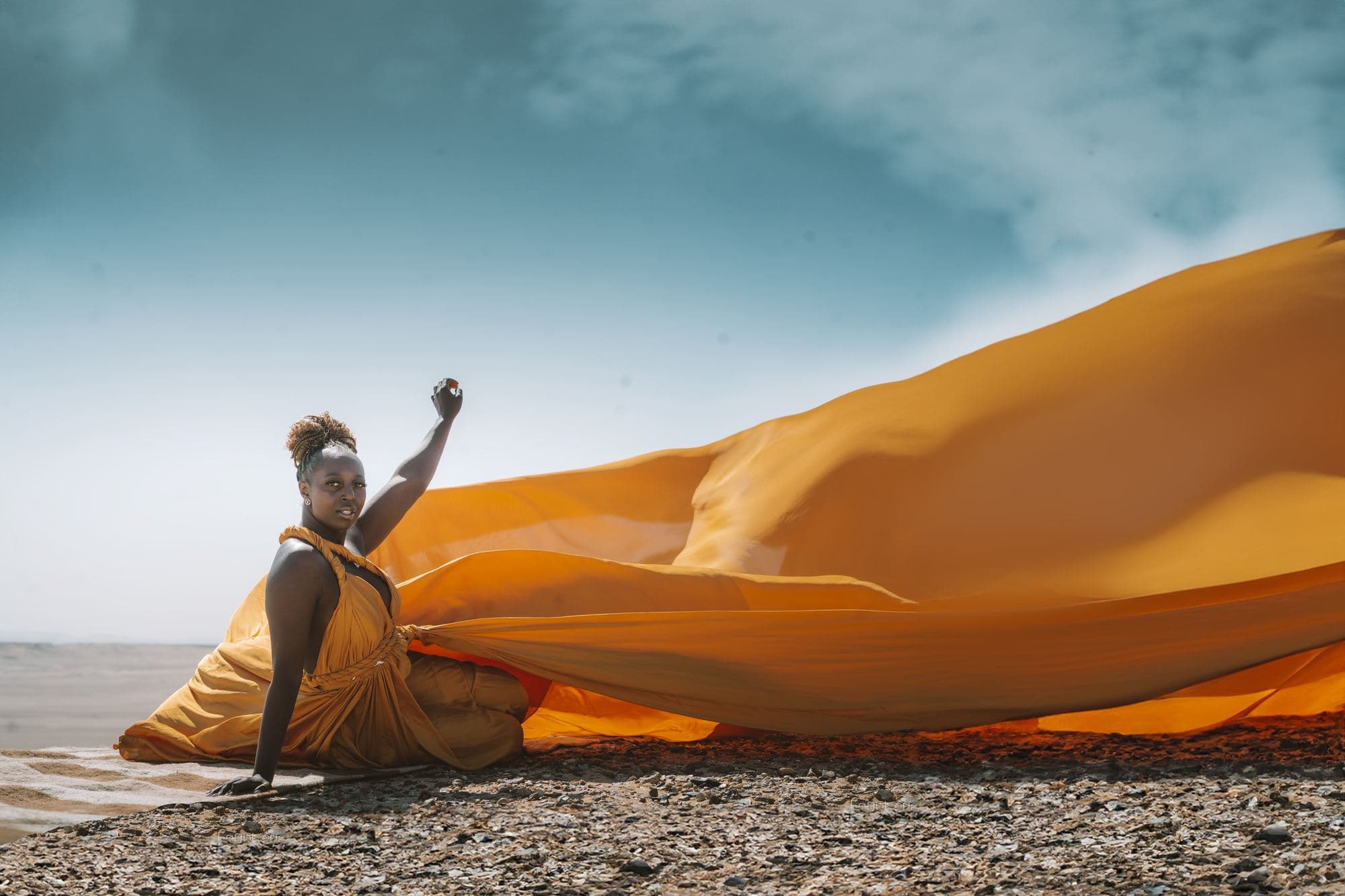 An amber dress on the shore at Fayoum, its train thrown out across the sand beside the water
