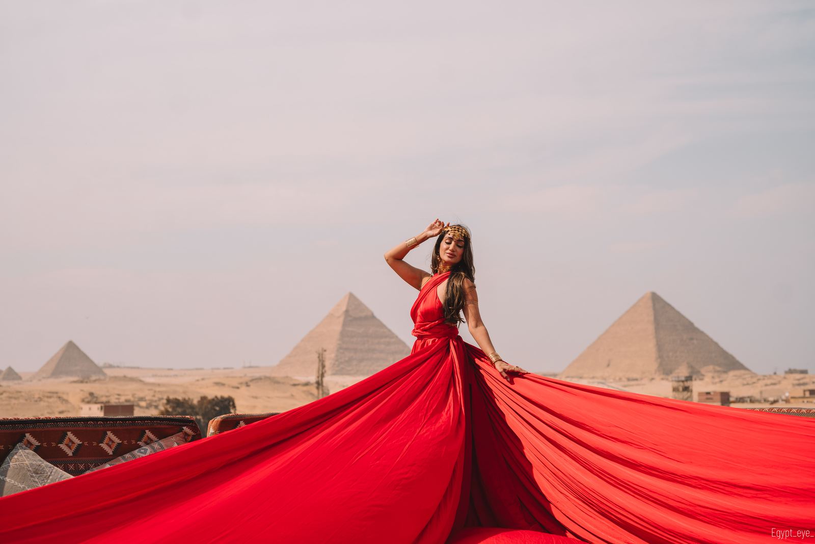 The Cherry dress on the Giza rooftop, its red train sweeping the full width of the frame with the pyramids behind