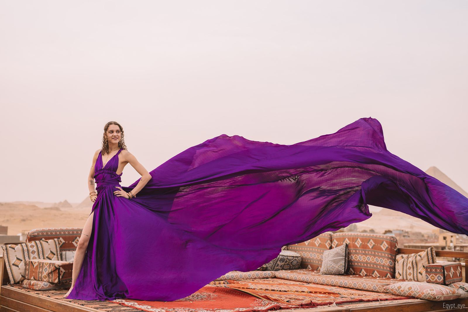 The Lavender dress with its violet train streaming sideways across the rooftop