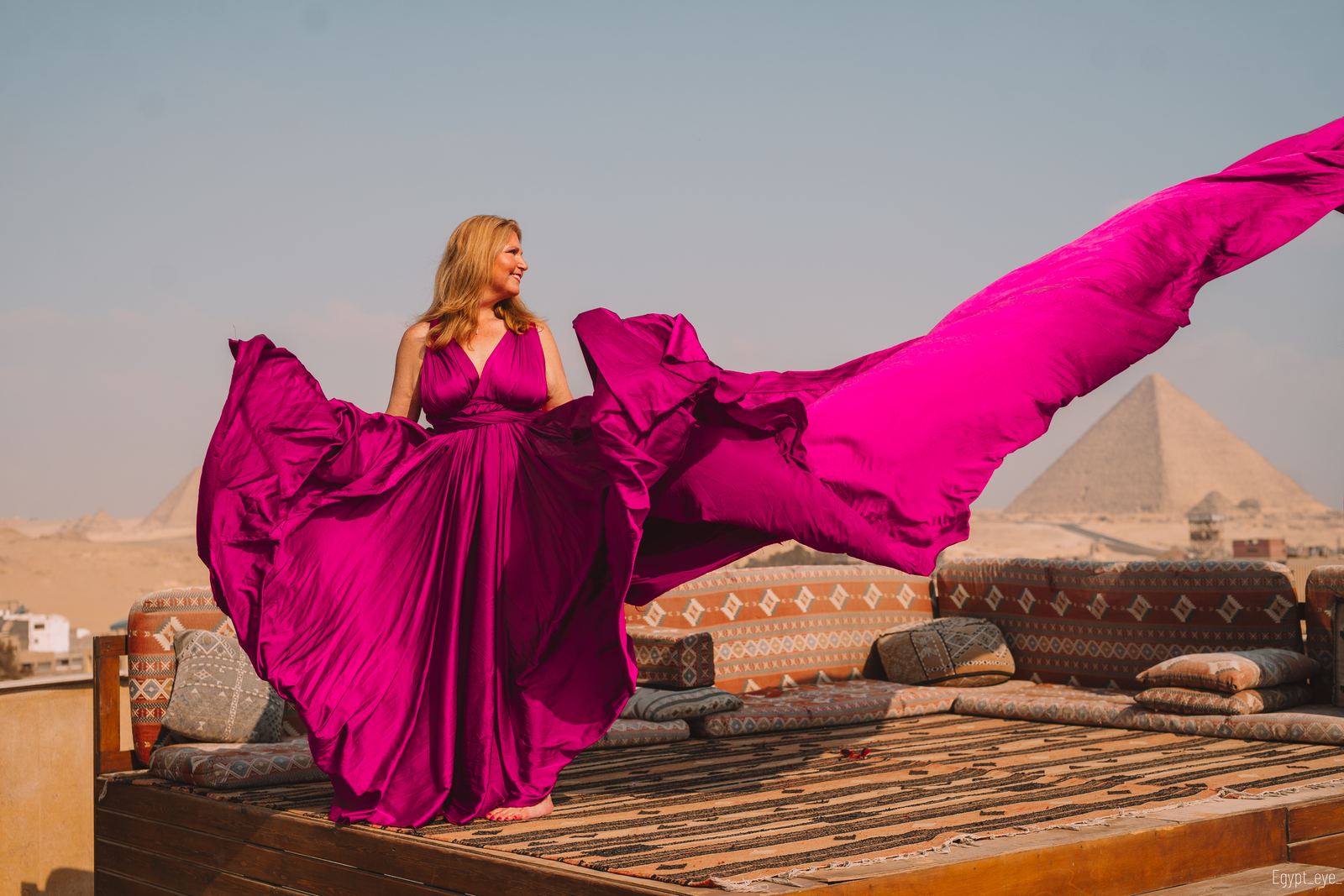 The Orchid dress on the rooftop, magenta silk thrown up into the air beside a pyramid