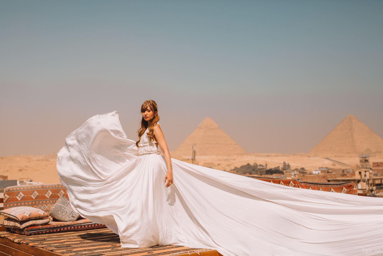 The Snowy dress lifting in the wind on the rooftop, white fabric bright against the desert